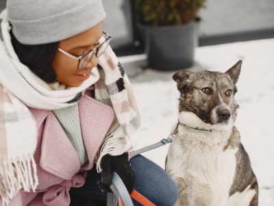 Cute african girl in a winter park. Woman in a pink coat. Lady with a dog.